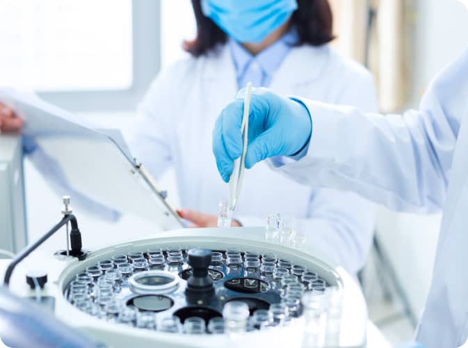 A lab technician is inserting a sample into a large centrifuge.