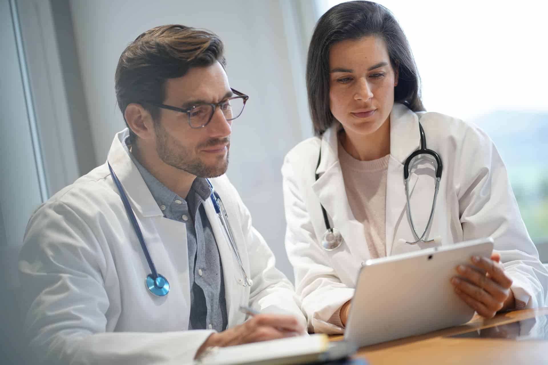 A male and female doctor going over notes on a tablet.