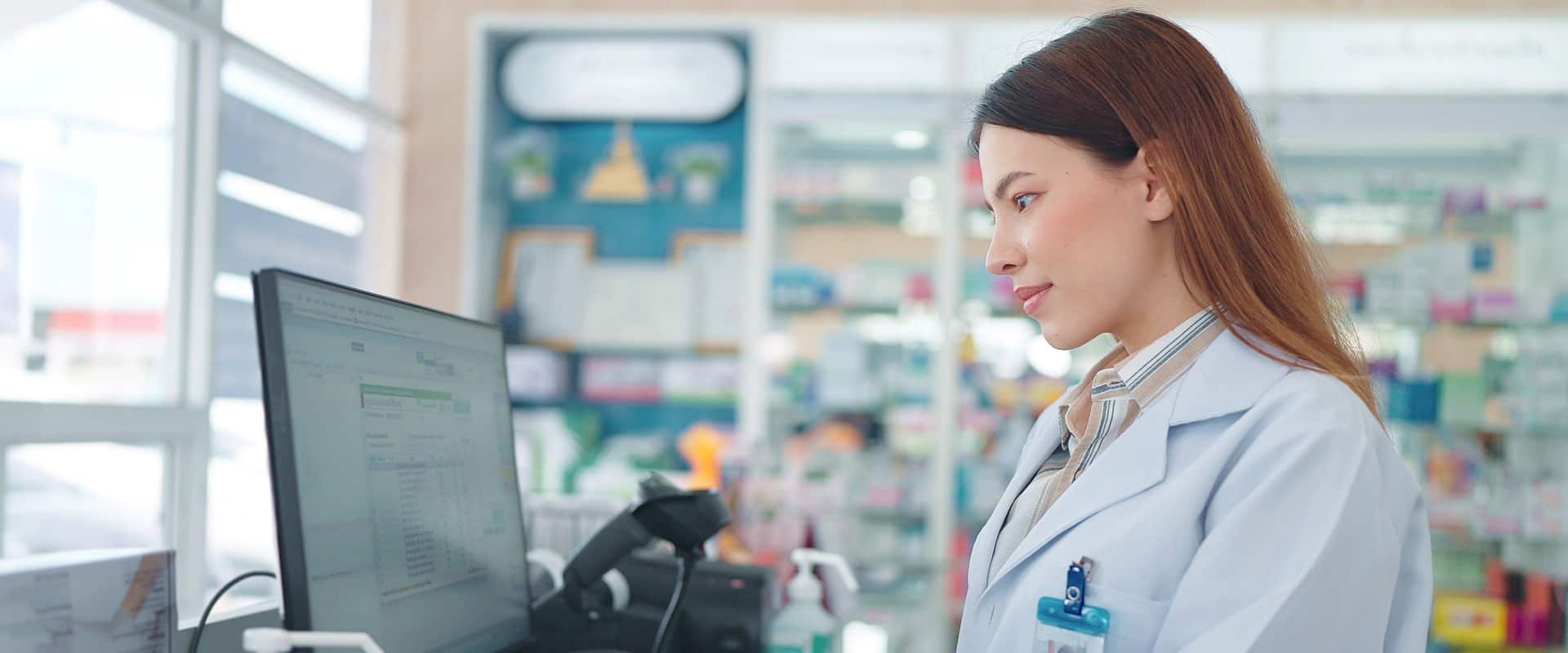 A woman in a lab coat is working at a computer.